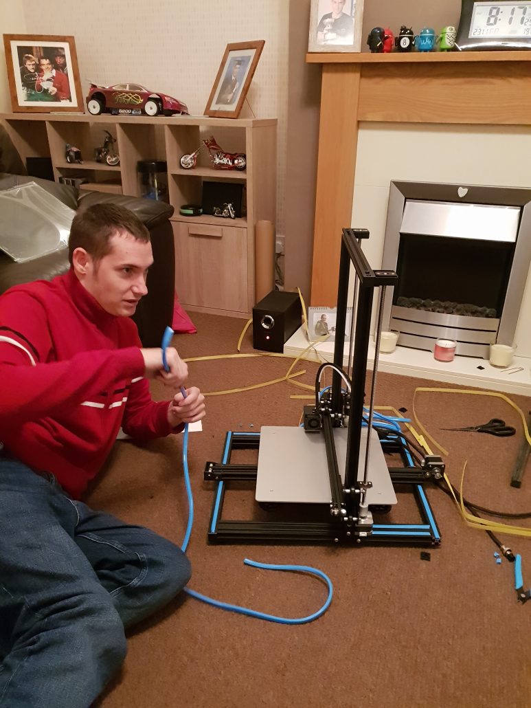 Man reclined on floor assembling a 3d printing